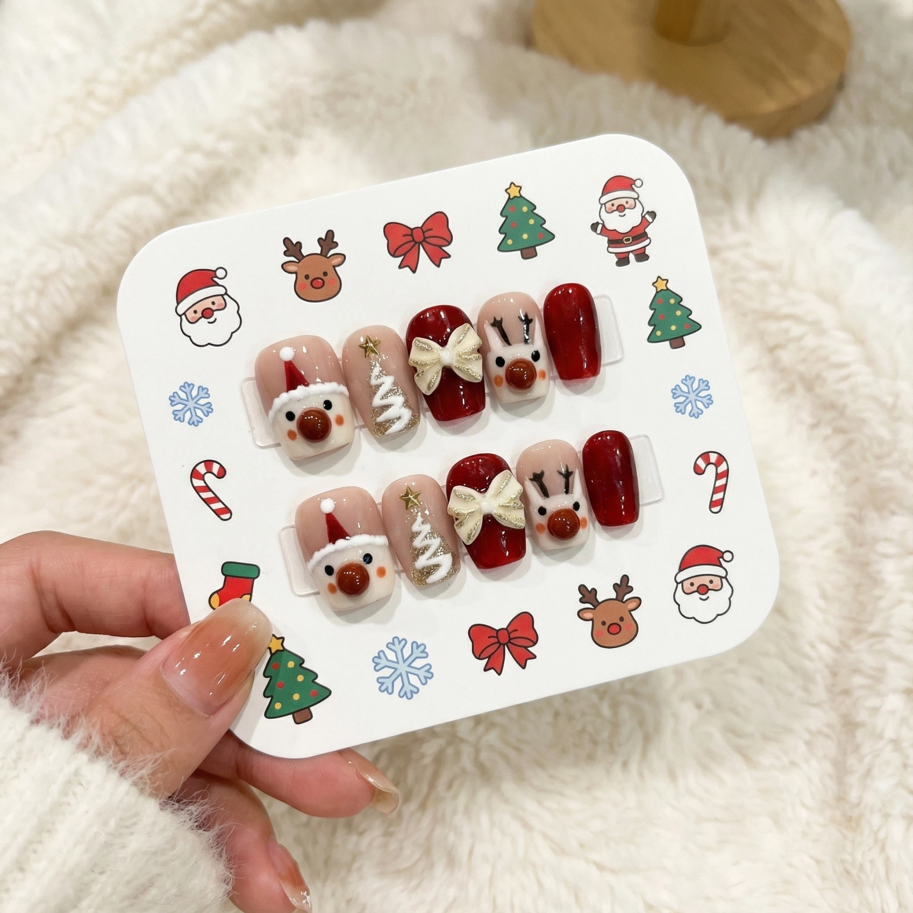 Christmas themed press on nail set on display card with Santa, tree, bow and reindeer designs in red