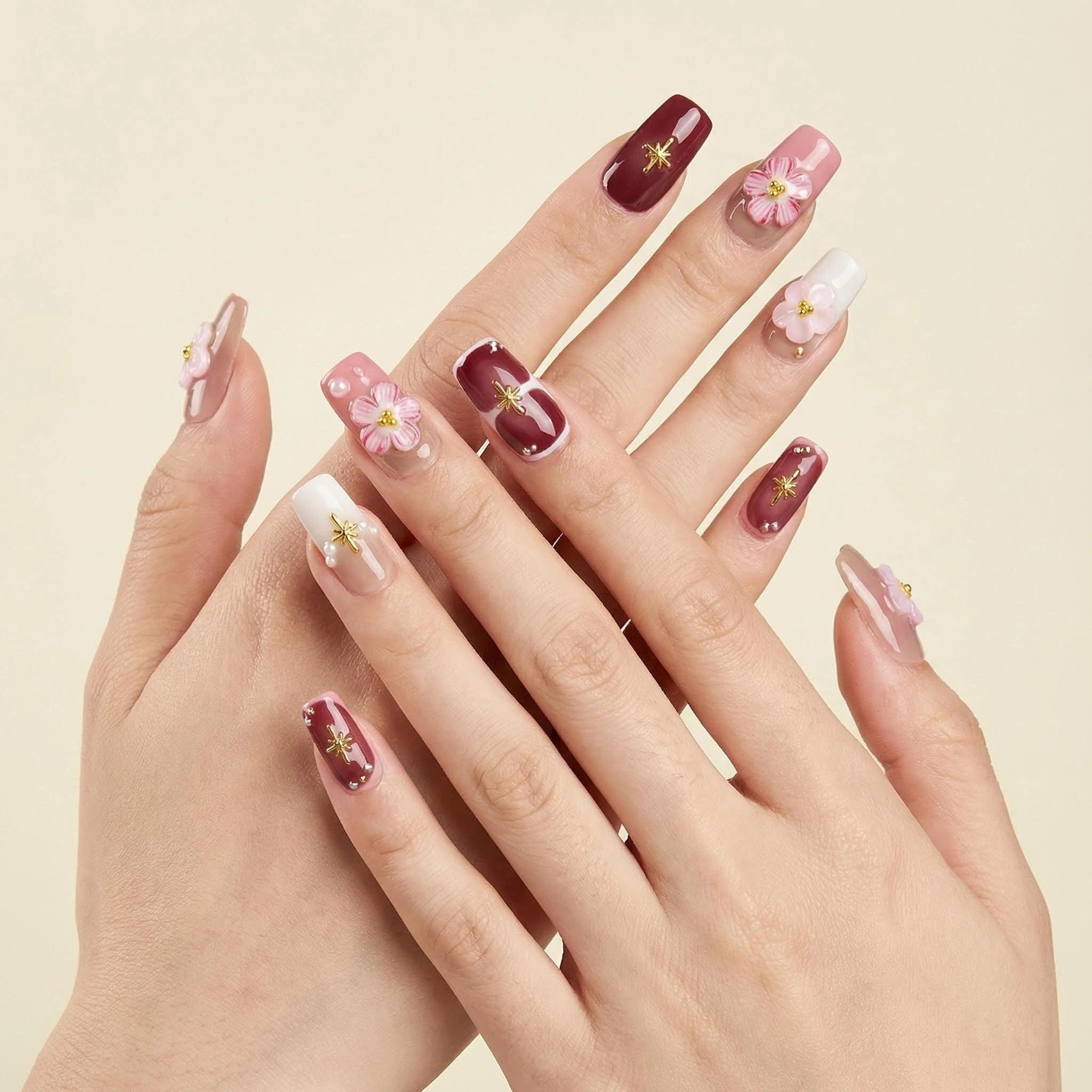 Floral press-on nails on hands in blush pink nude tones with pearl and gold accents, glossy salon-style finish