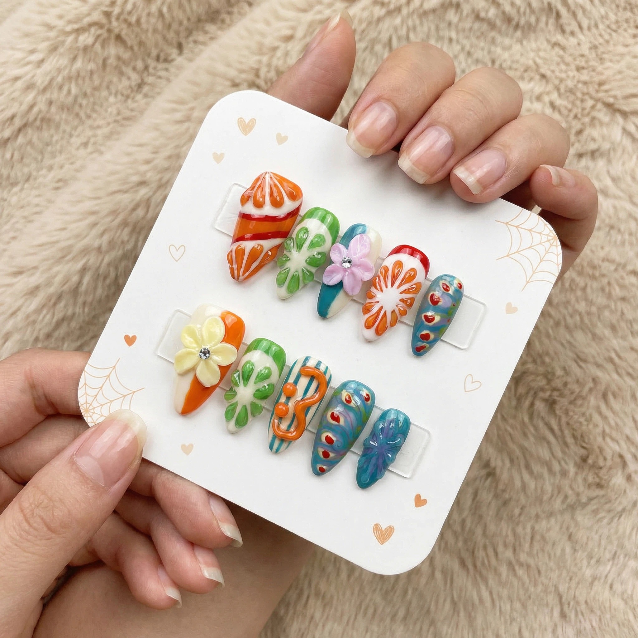 Bright tropical press-on nails set with orange slices, blue accents, and floral designs