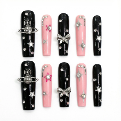 alt="Flat lay of black and pink long coffin press on nails with silver star, planet and bow rhinestone charms"