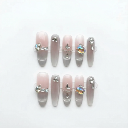 Flat lay of pink nude long coffin press-on nail set with clear tips and crystal accents