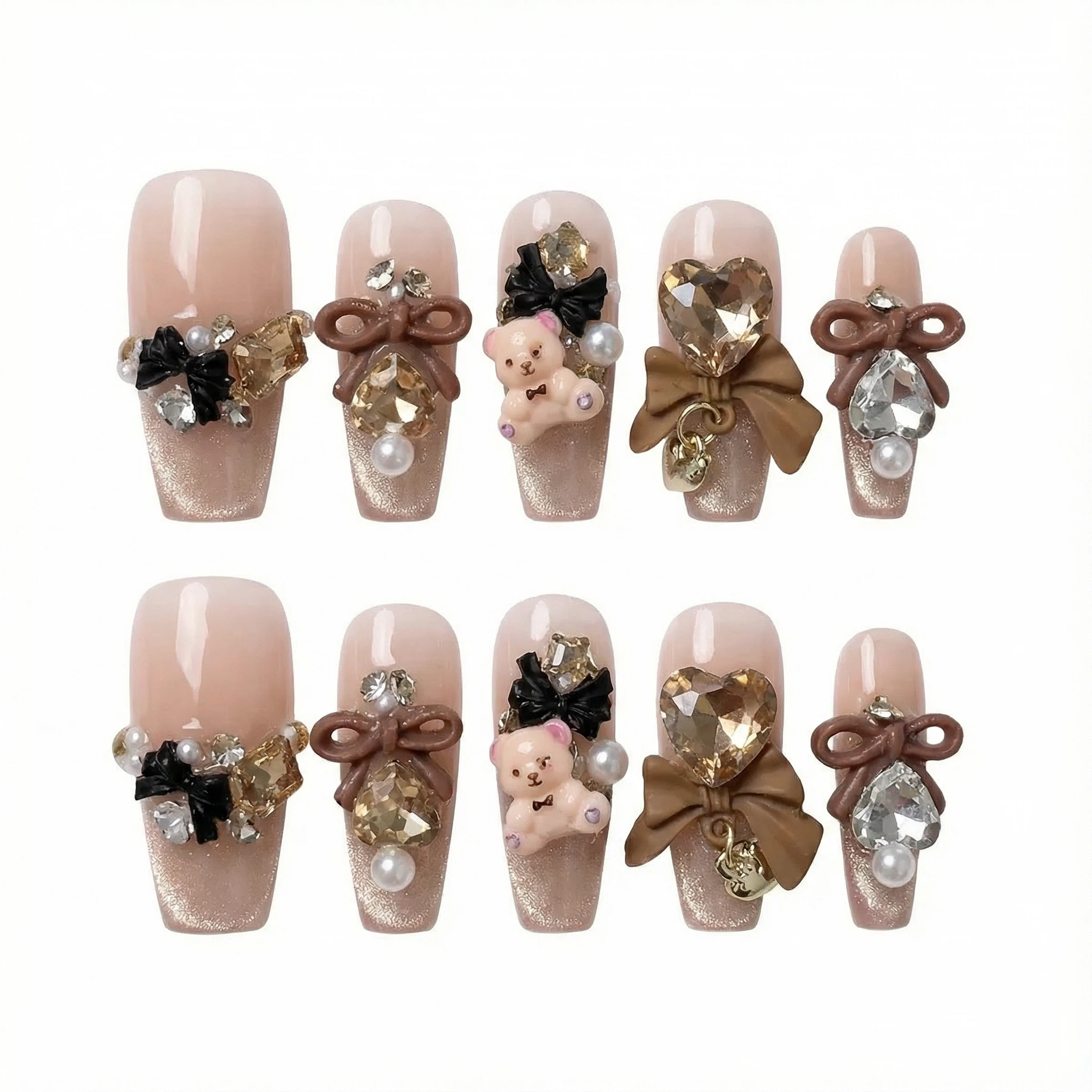 Full set of 10 nude press-on nails with black details, bow charm, pearls and rhinestones arranged on white background