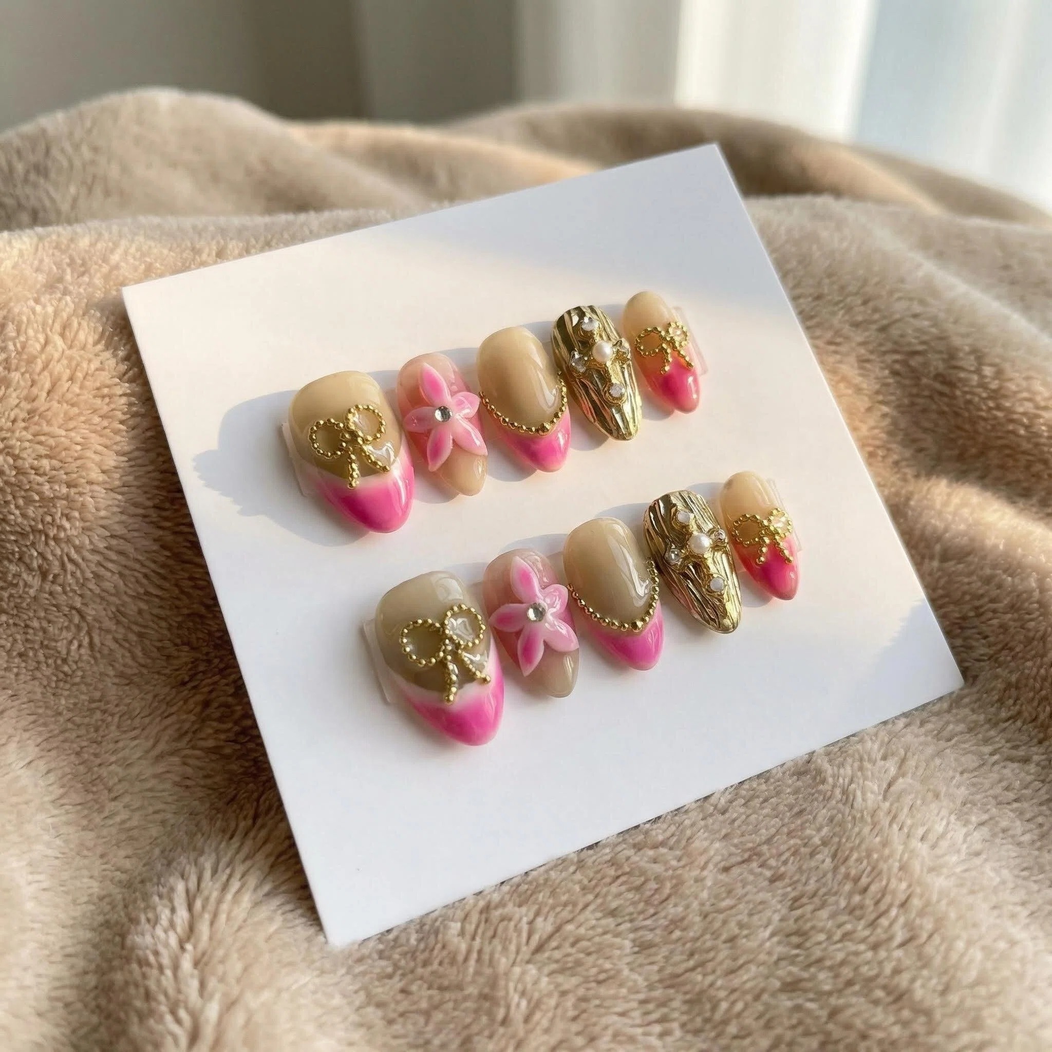 Cover: Hand holding rose champagne pink French tip press-on nails set with gold foil accents