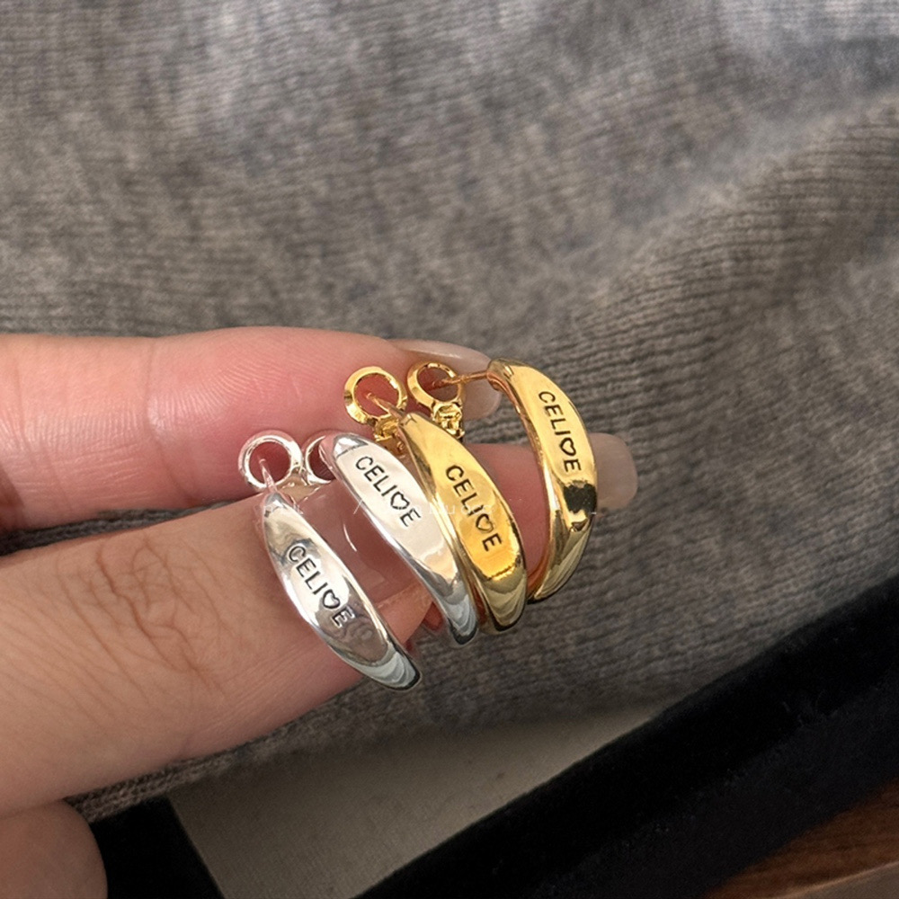Gold and silver tone engraved hoop earrings displayed together in hand