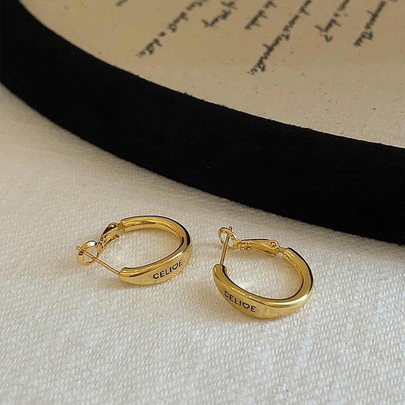 Pair of gold tone hoop earrings displayed on light fabric