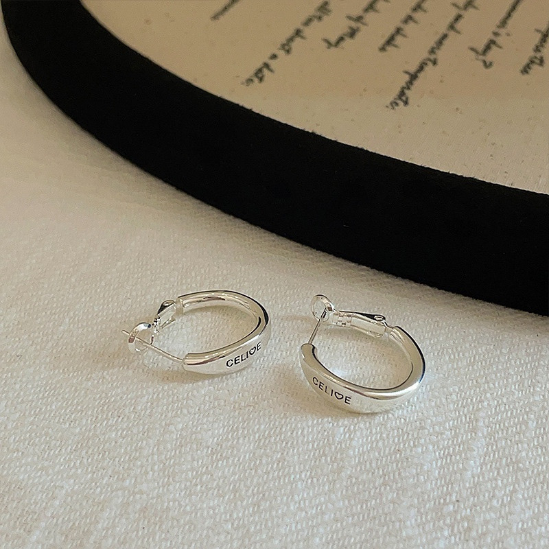 Side view of gold tone engraved hoop earring worn on ear