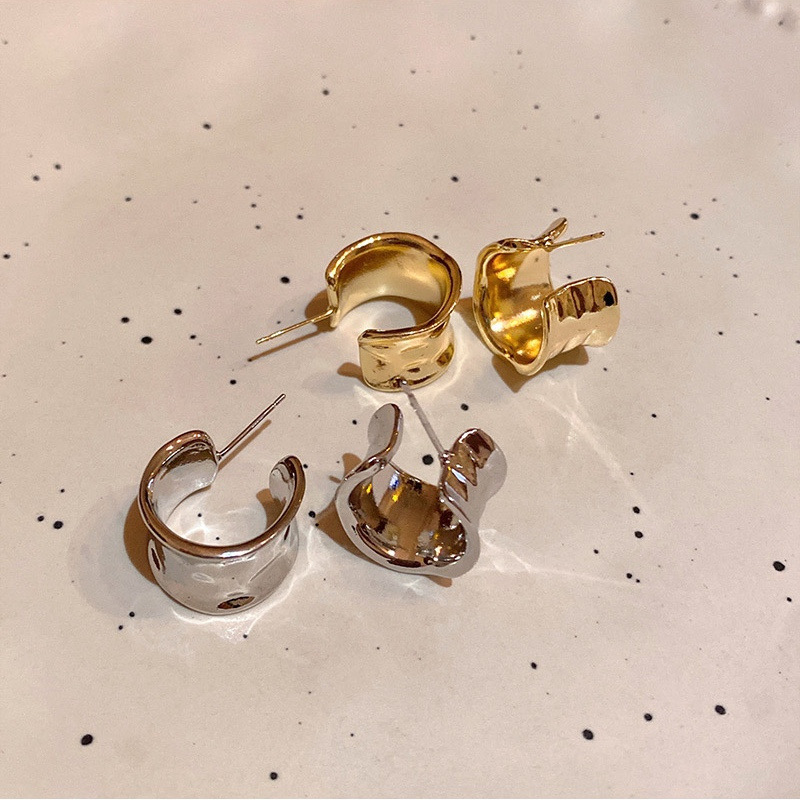 Gold and silver wide hoop earrings displayed together on a light speckled surface