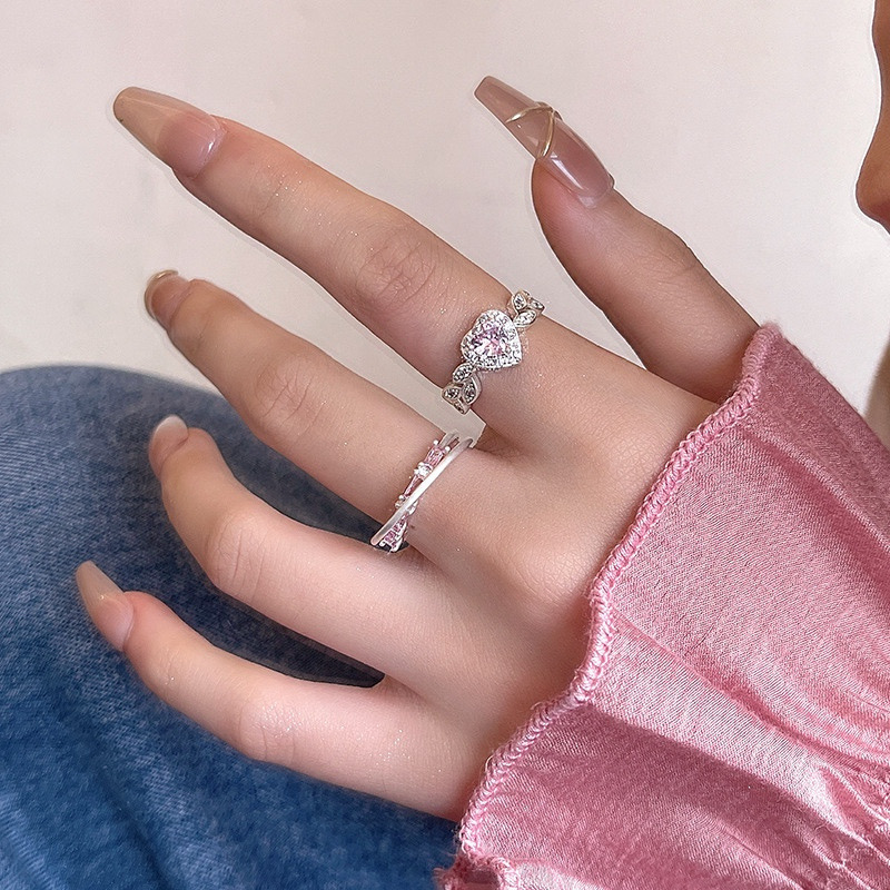 Silver pink heart rhinestone and curved open ring set displayed on a white ceramic dish