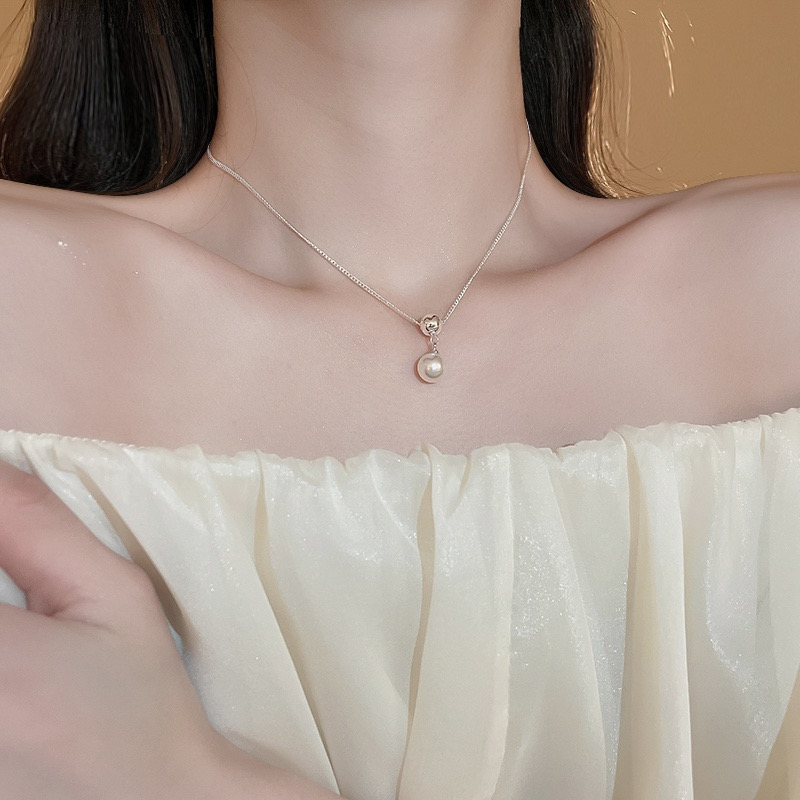 Woman wearing a minimalist silver ball and faux pearl necklace with a white off-shoulder dress