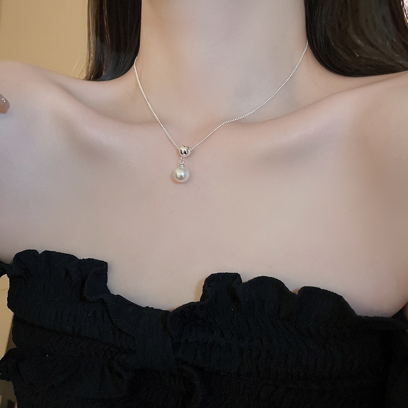 Silver-tone faux pearl pendant necklace displayed inside a cream jewelry tray