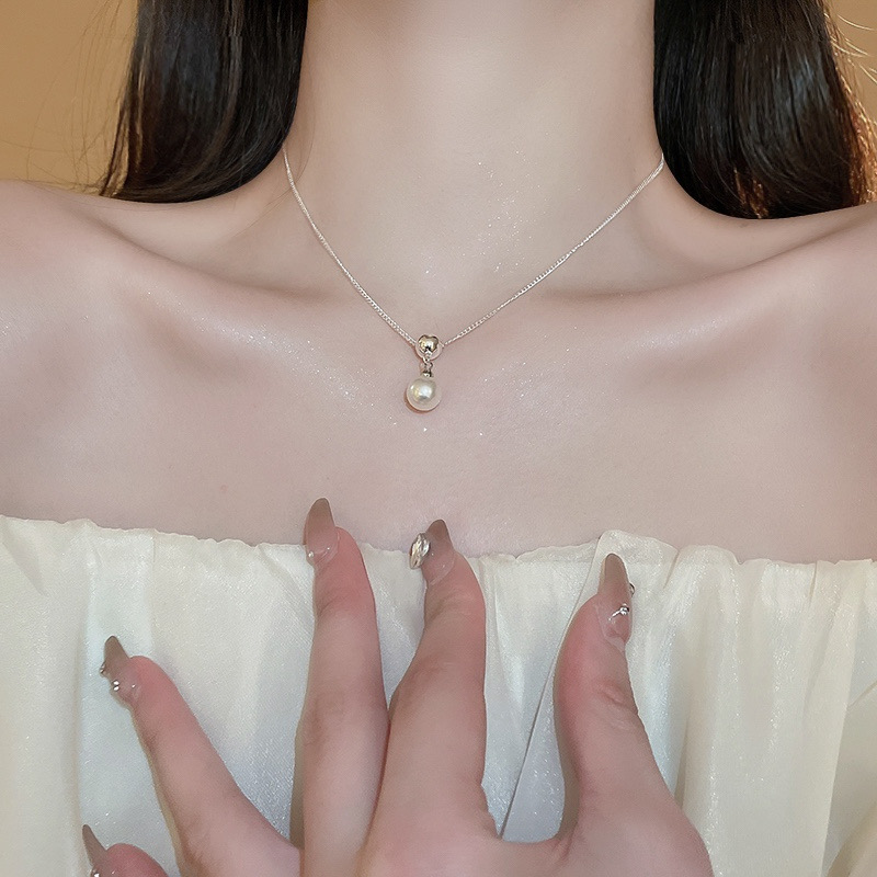 Woman wearing a silver ball faux pearl pendant necklace with a black off-shoulder top