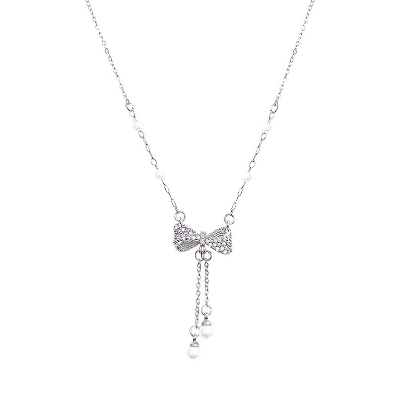 Silver zircon bow pearl tassel necklace with sparkling bow pendant and white faux pearl accents on white background