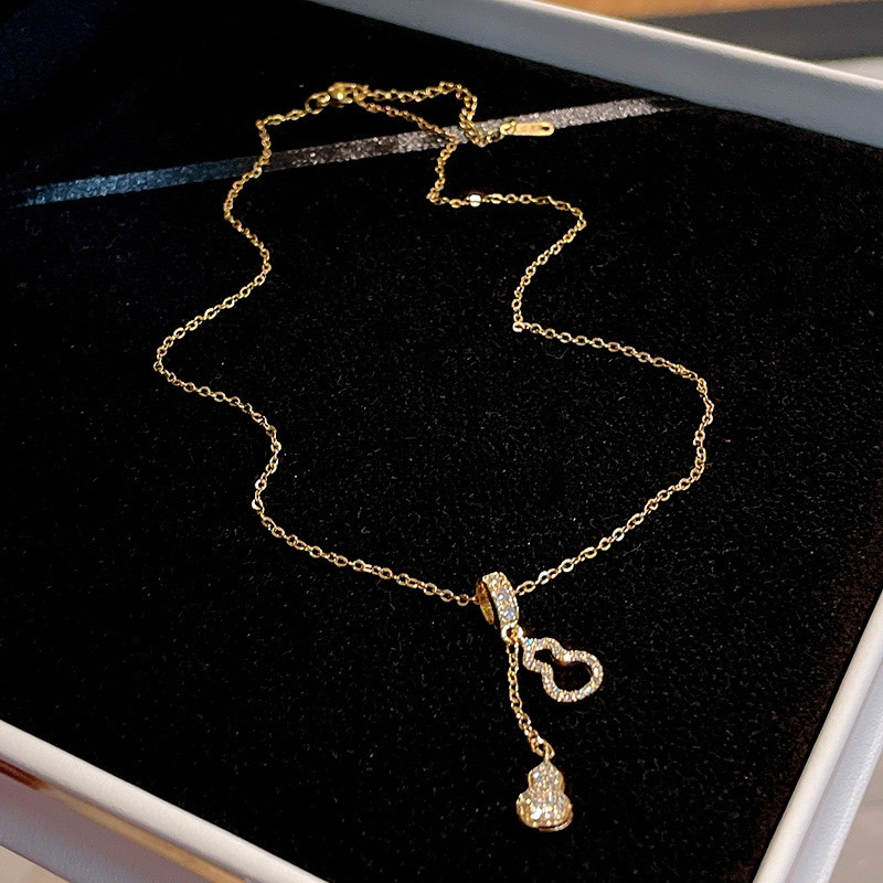 Gold zircon gourd pendant necklace with delicate chain displayed on black velvet background