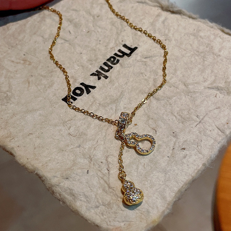Detailed view of gold zircon gourd necklace with sparkling pendant and asymmetrical chain design