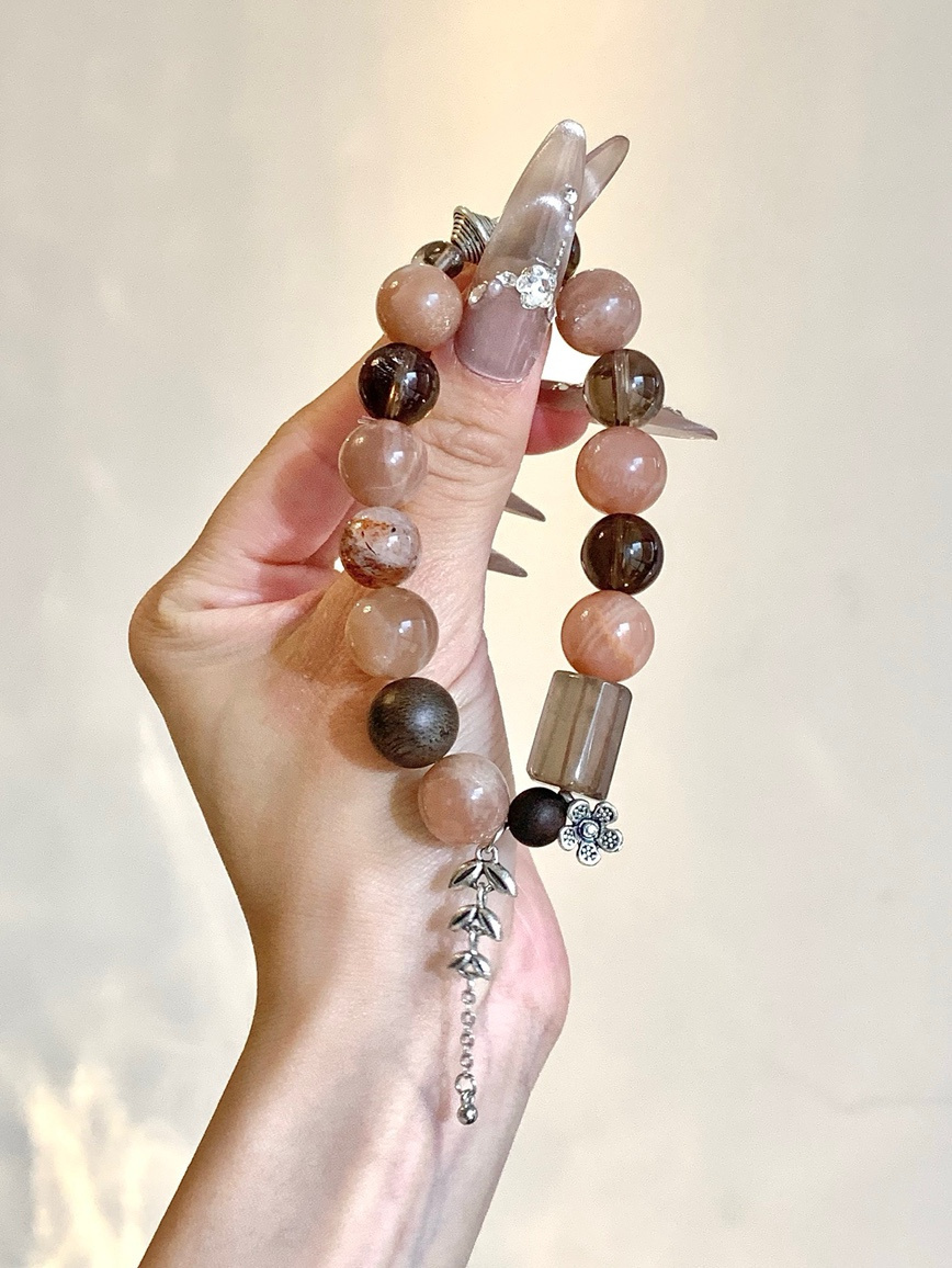 Close-up of moonstone and black tourmaline quartz beads with silver leaf charm