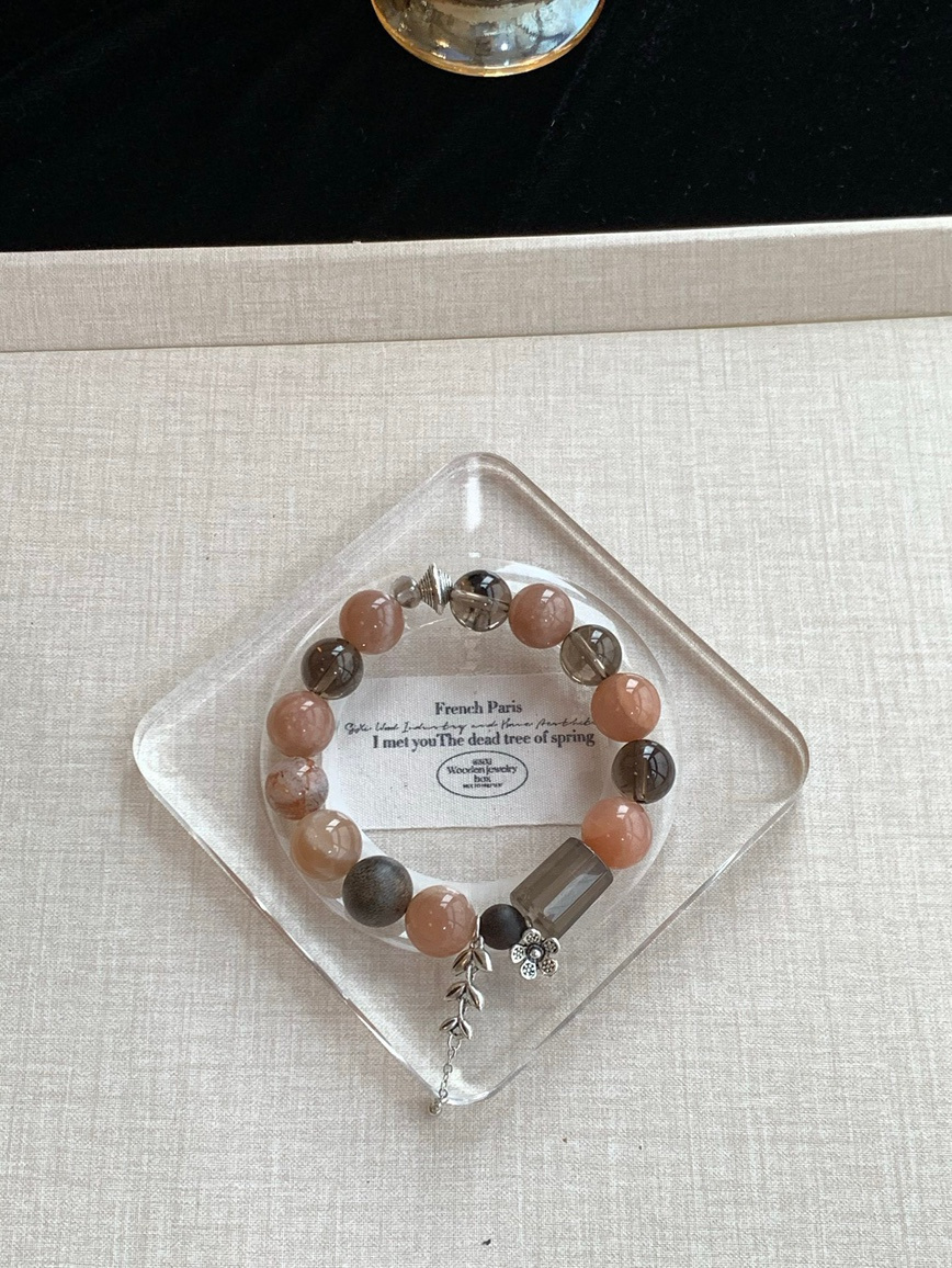 Handmade gemstone bracelet on beige surface with natural shadow