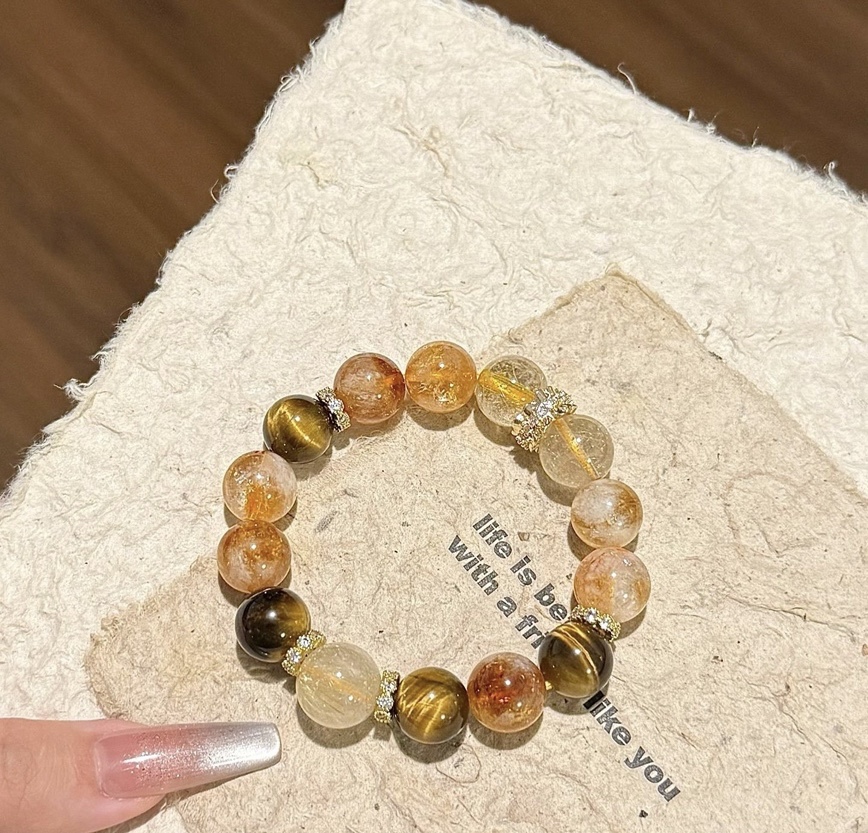 Luxury gemstone bracelet with golden tones displayed with elegant manicure