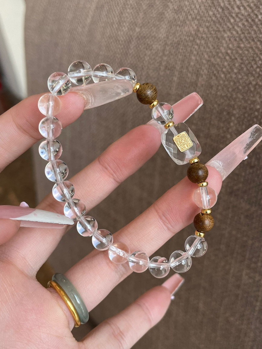 Close-up – natural clear quartz beads showing high transparency and gold charm details.