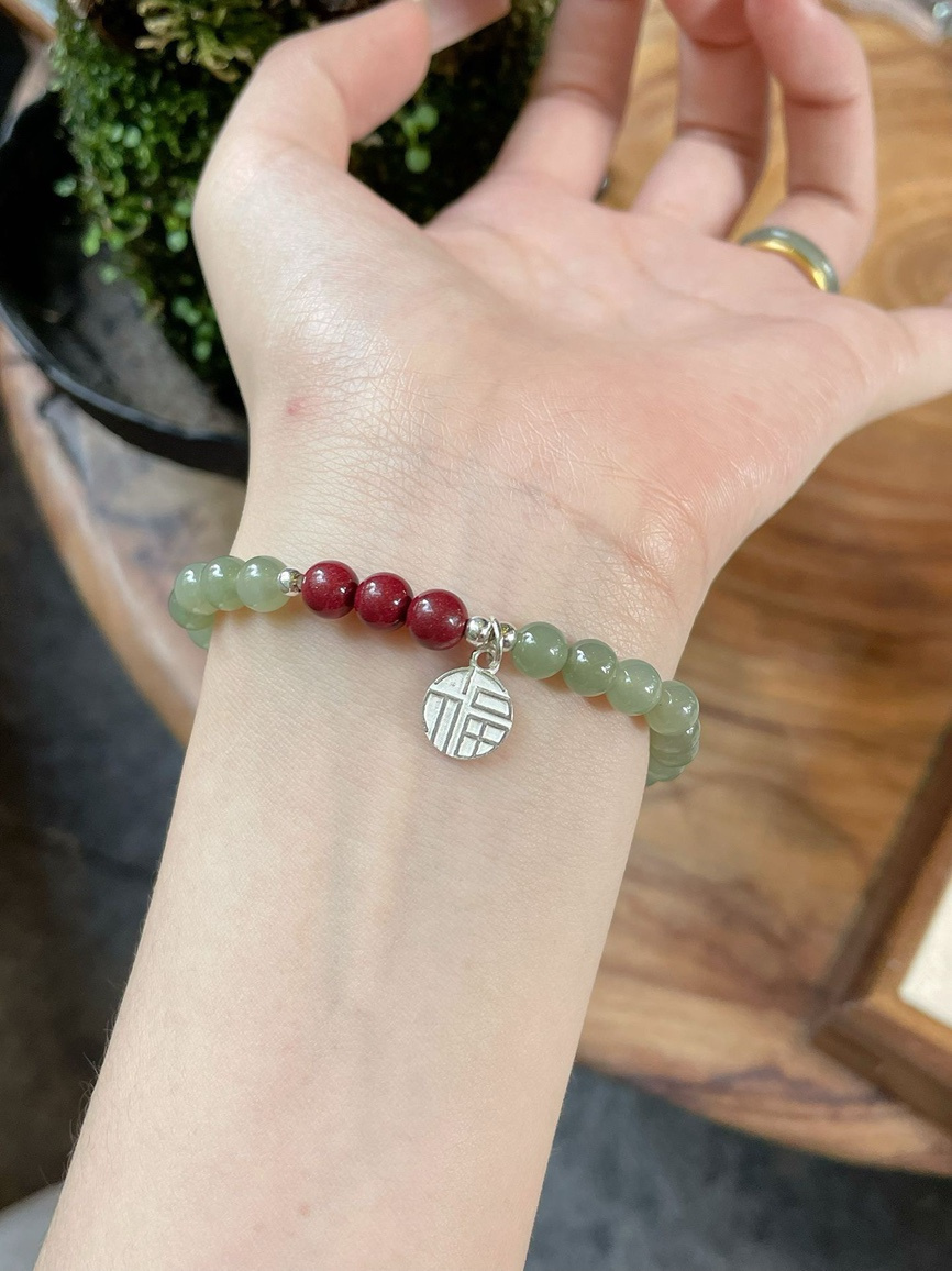 Model wearing Hetian jade and cinnabar bracelet on wrist showing natural elegance