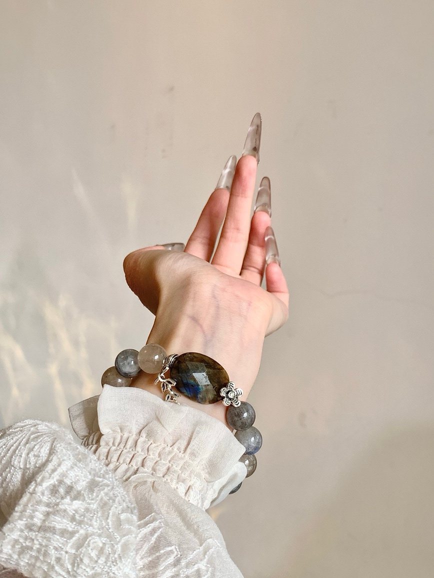 Wrist wearing Moonstone and Rutilated Quartz bracelet under natural light
