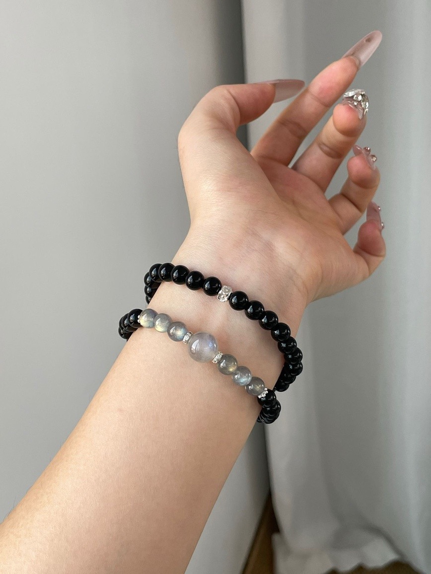 Wrist wearing Obsidian and Moonstone energy bracelet under soft light