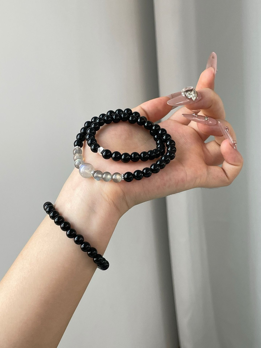 Hand holding gemstone bracelet against minimalist background