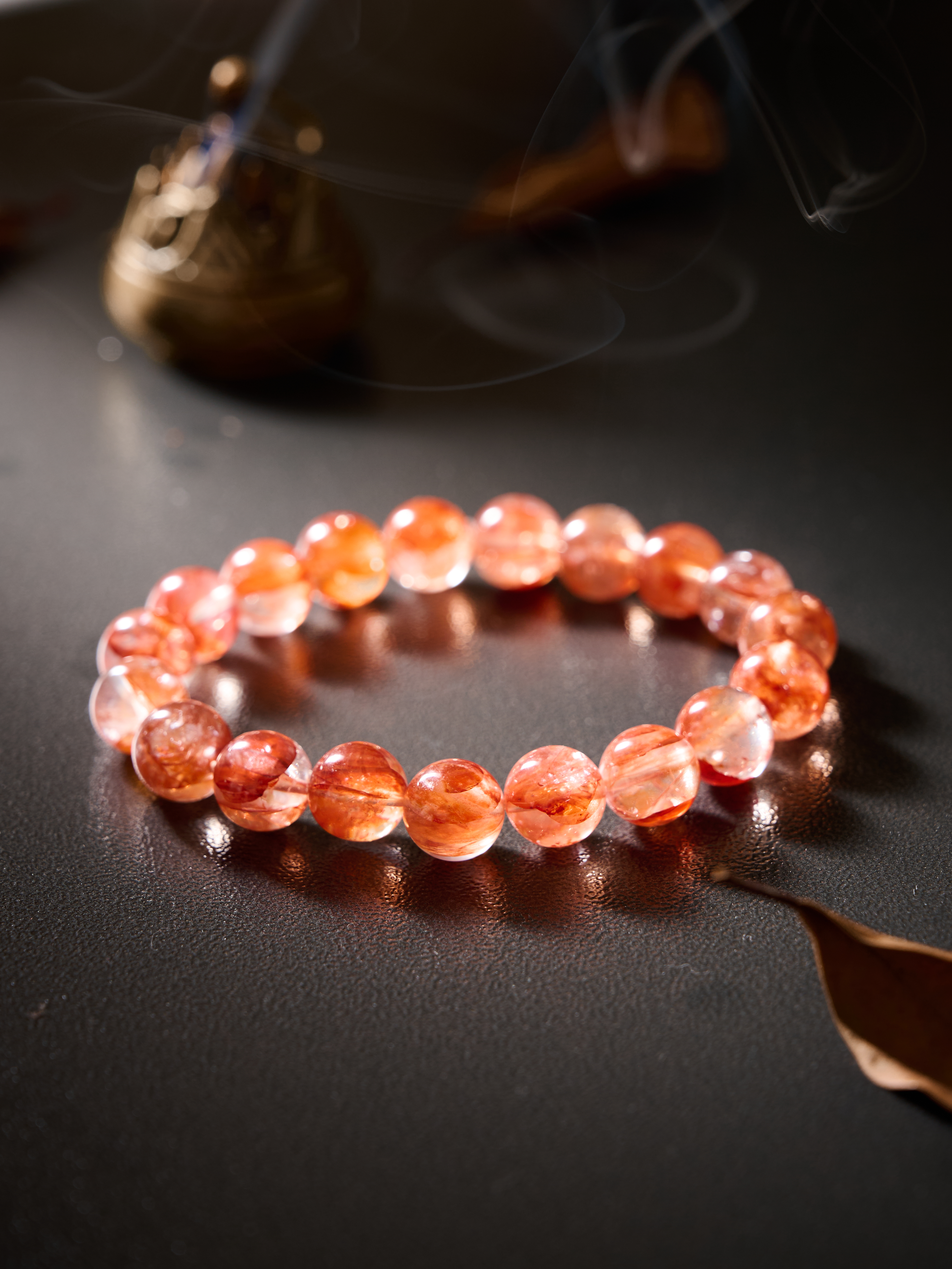 Flat lay circle on neutral background showing warm scarlet inclusions inside clear quartz beads