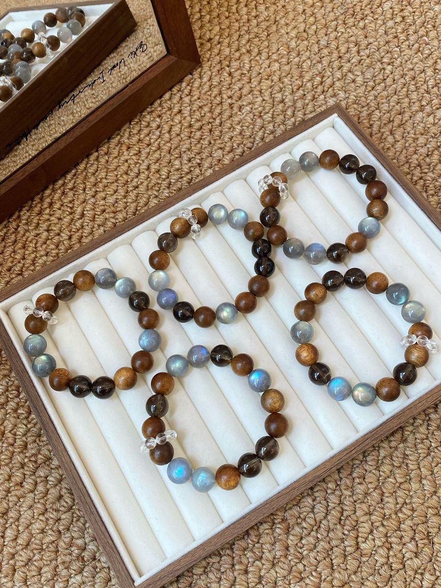 Main view – agarwood, smoky quartz, and gray moonstone bracelet displayed in wooden jewelry tray.