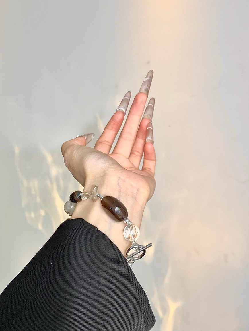 Model wearing smoky quartz and pearl bracelet with black outfit