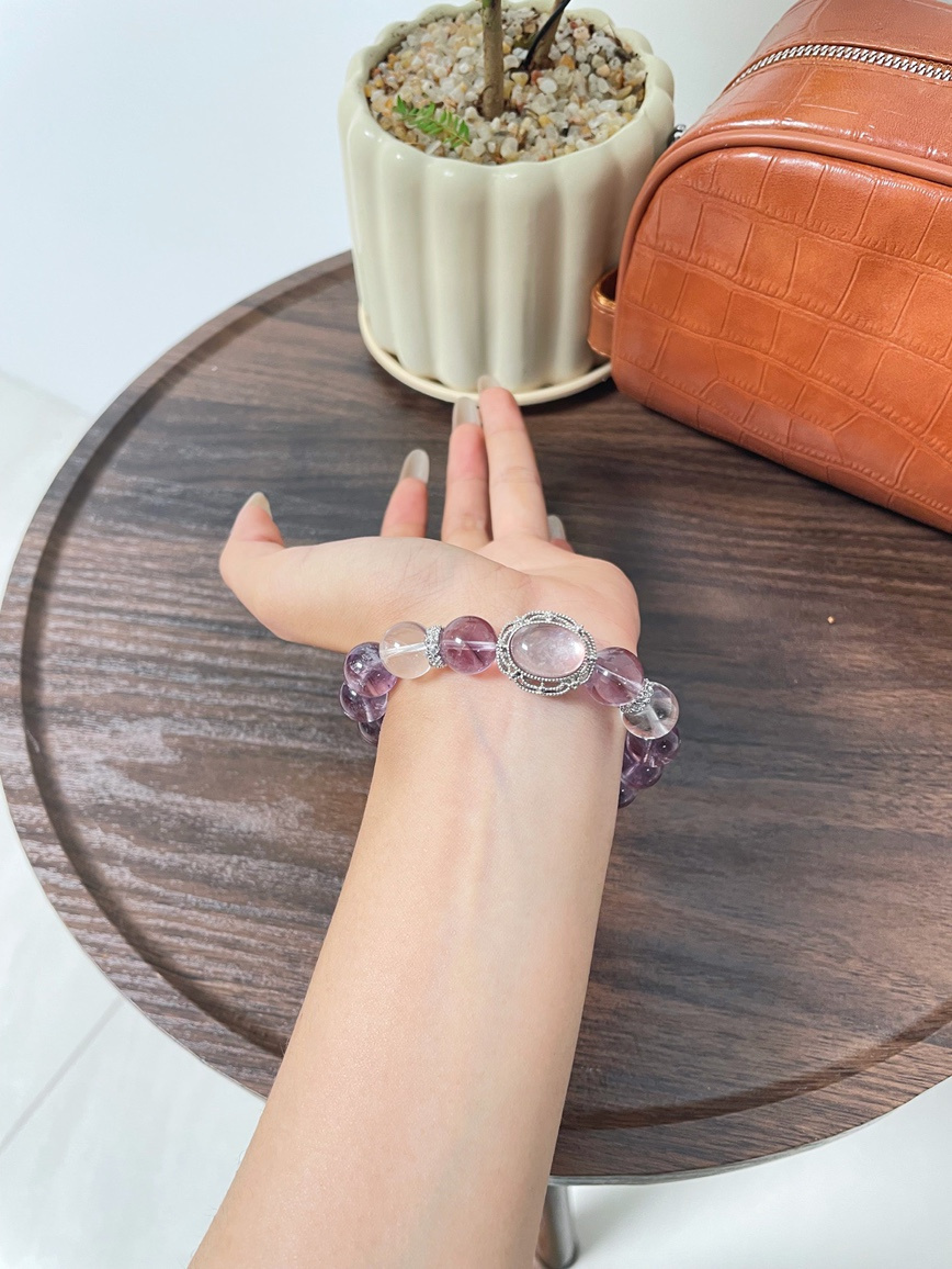 Wrist wearing purple gemstone bracelet with silver centerpiece