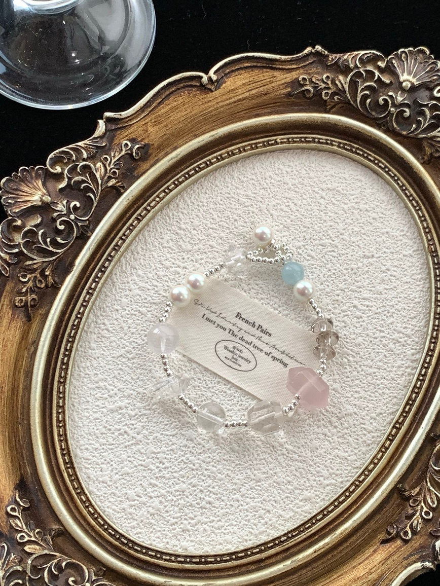 Flat-lay photo of the rose quartz bracelet with vintage frame background.