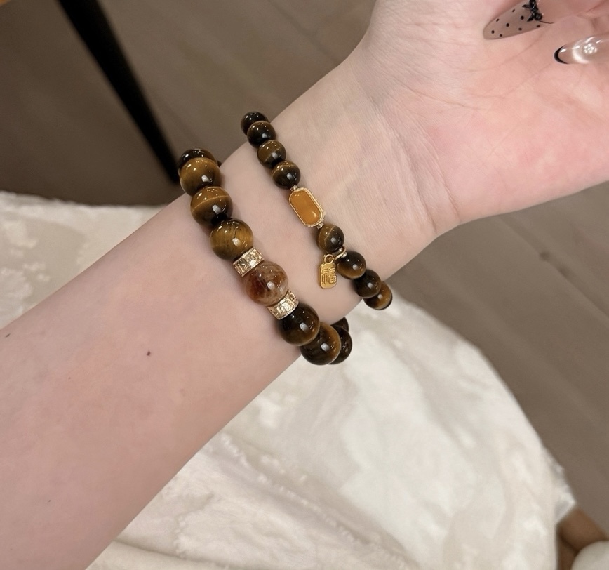 Stacked Tiger’s Eye bracelets featuring gold-plated charm details