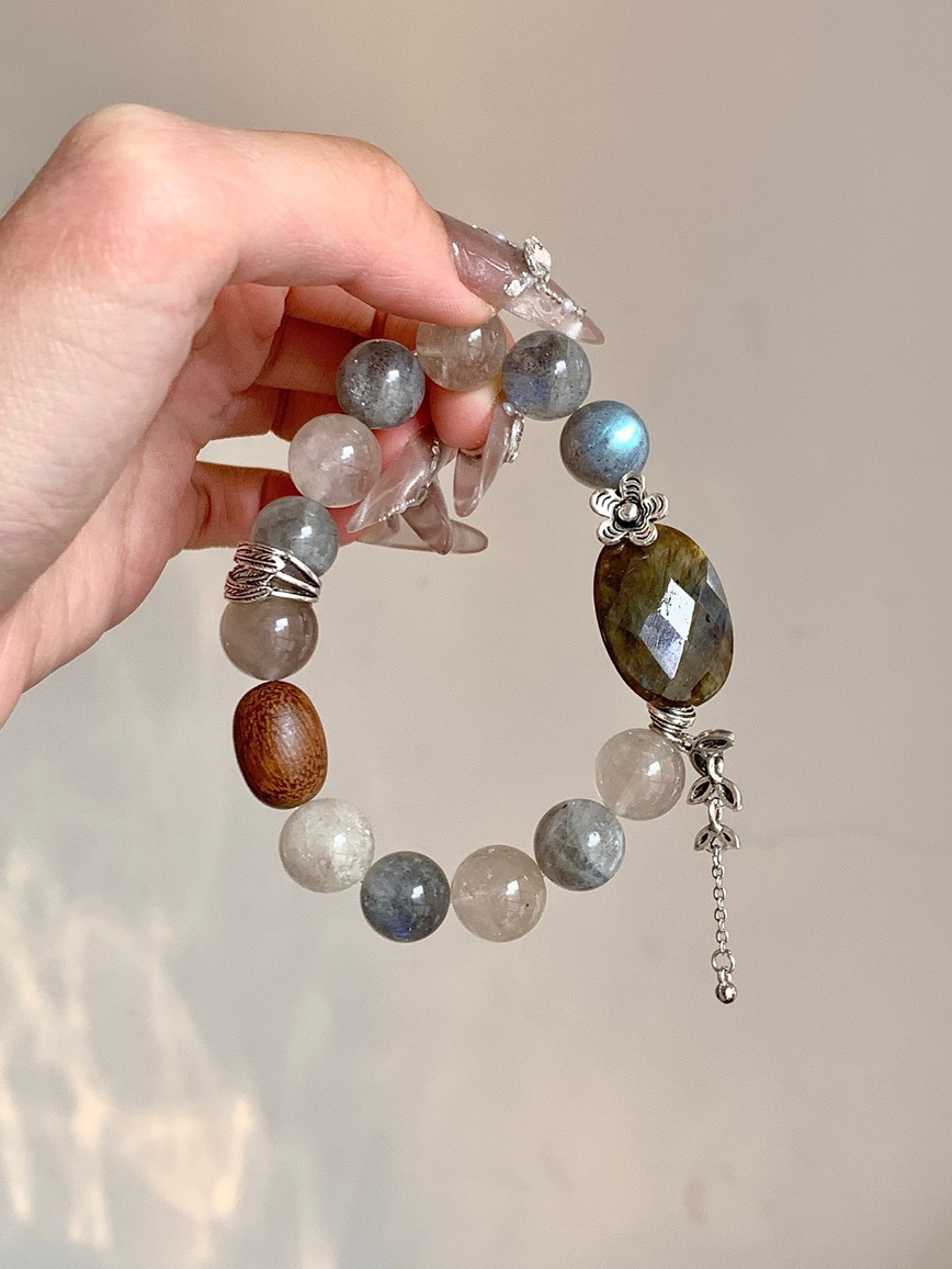 Hand holding natural Moonstone bracelet with close view of labradorite-like glow