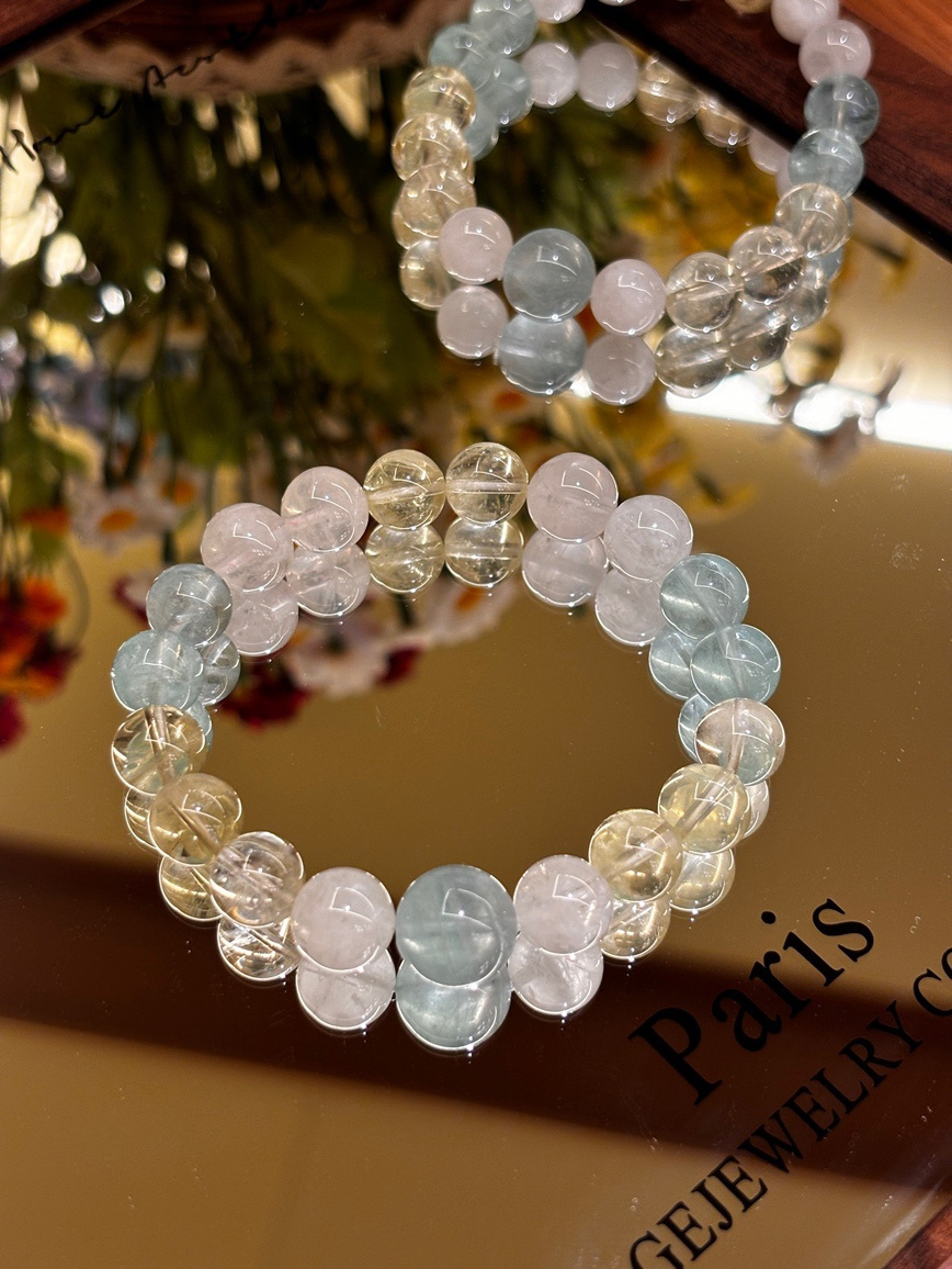 Aquamarine, citrine, and clear quartz bracelet displayed on a mirror surface