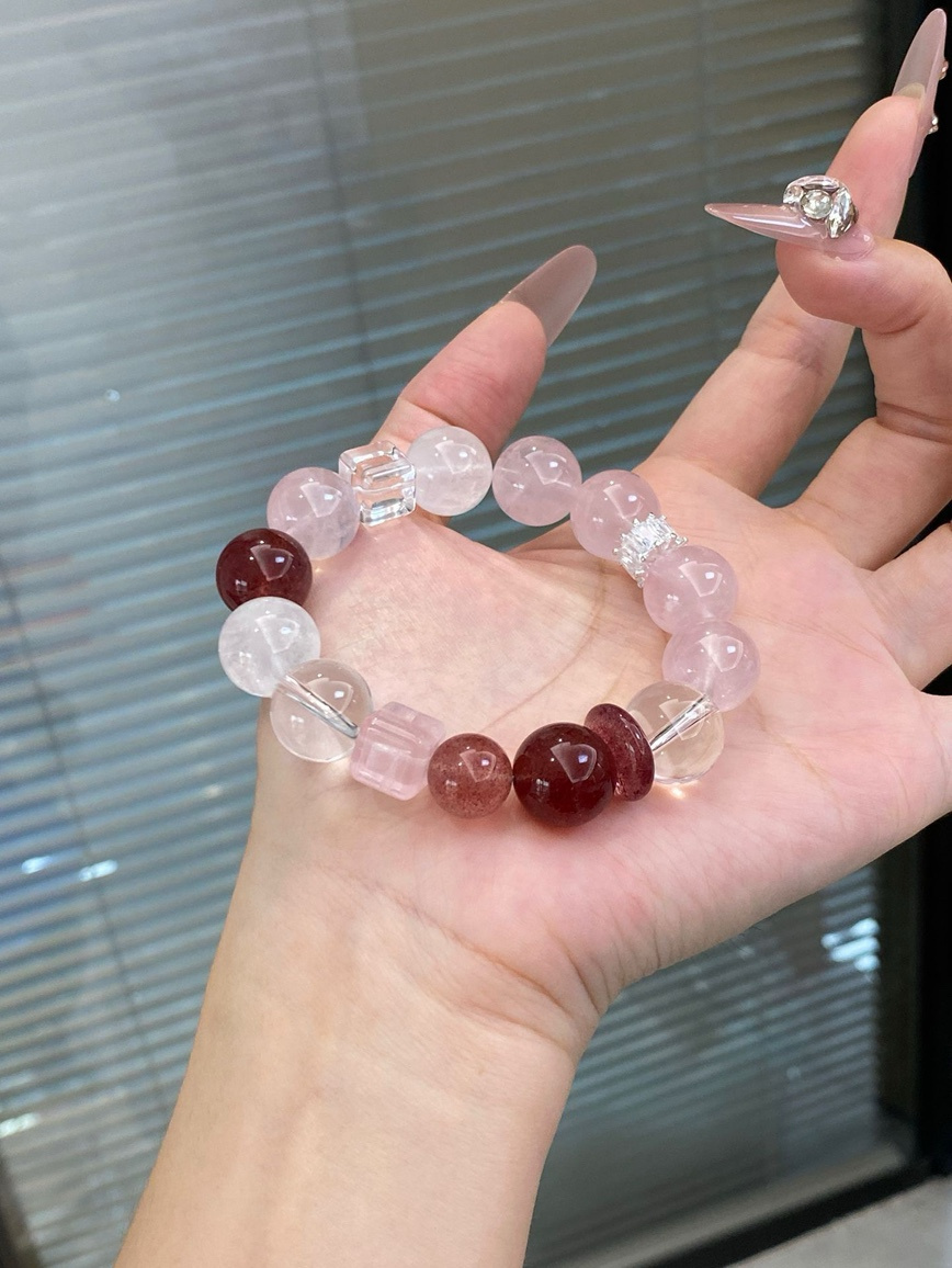 Hand holding pink crystal bracelet under natural light
