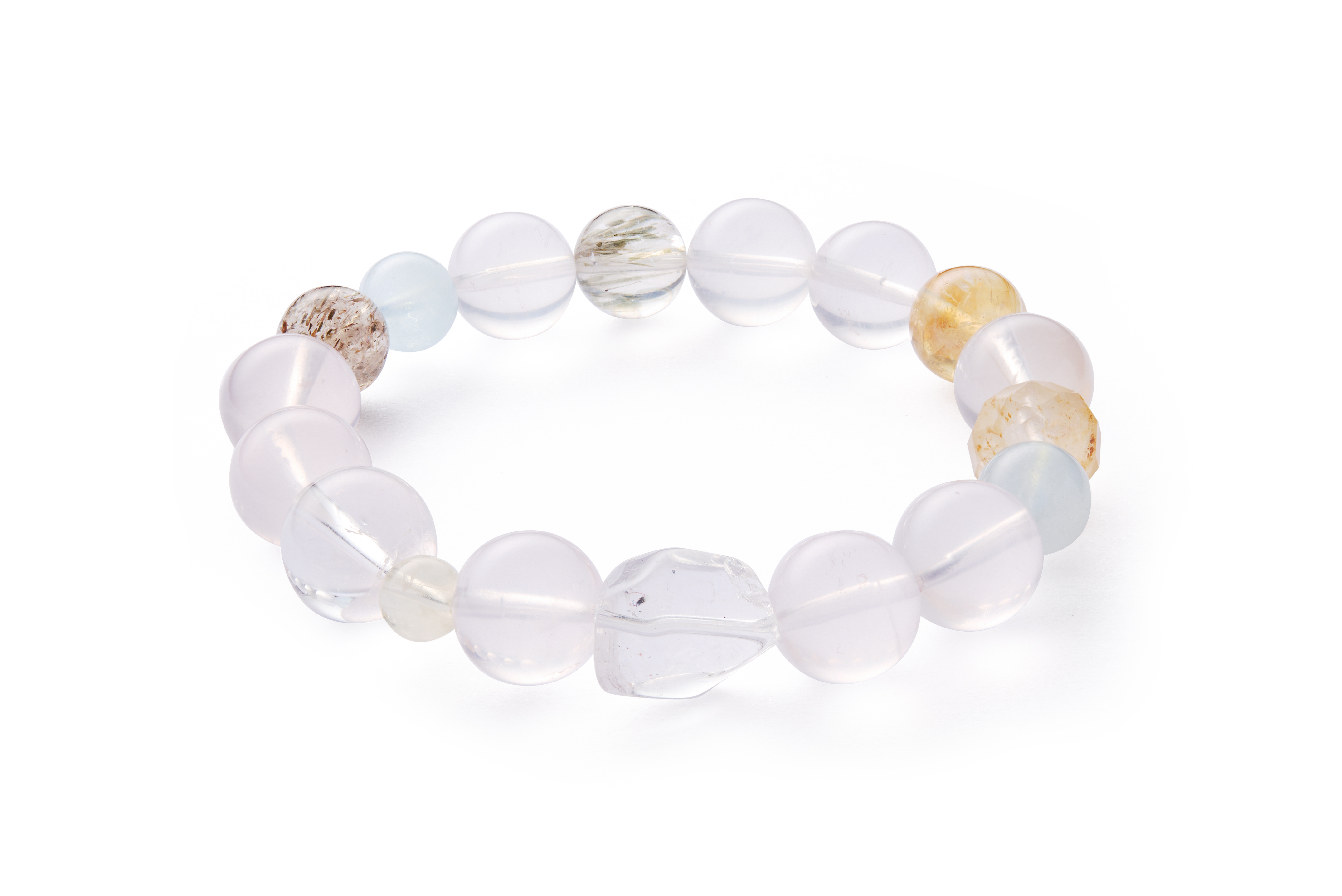 Flat lay with soft shadows highlighting polished clear quartz and soft-blue aquamarine beads