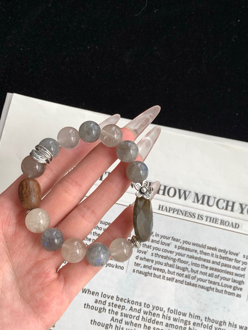 Hand holding natural Moonstone bracelet with close view of labradorite-like glow