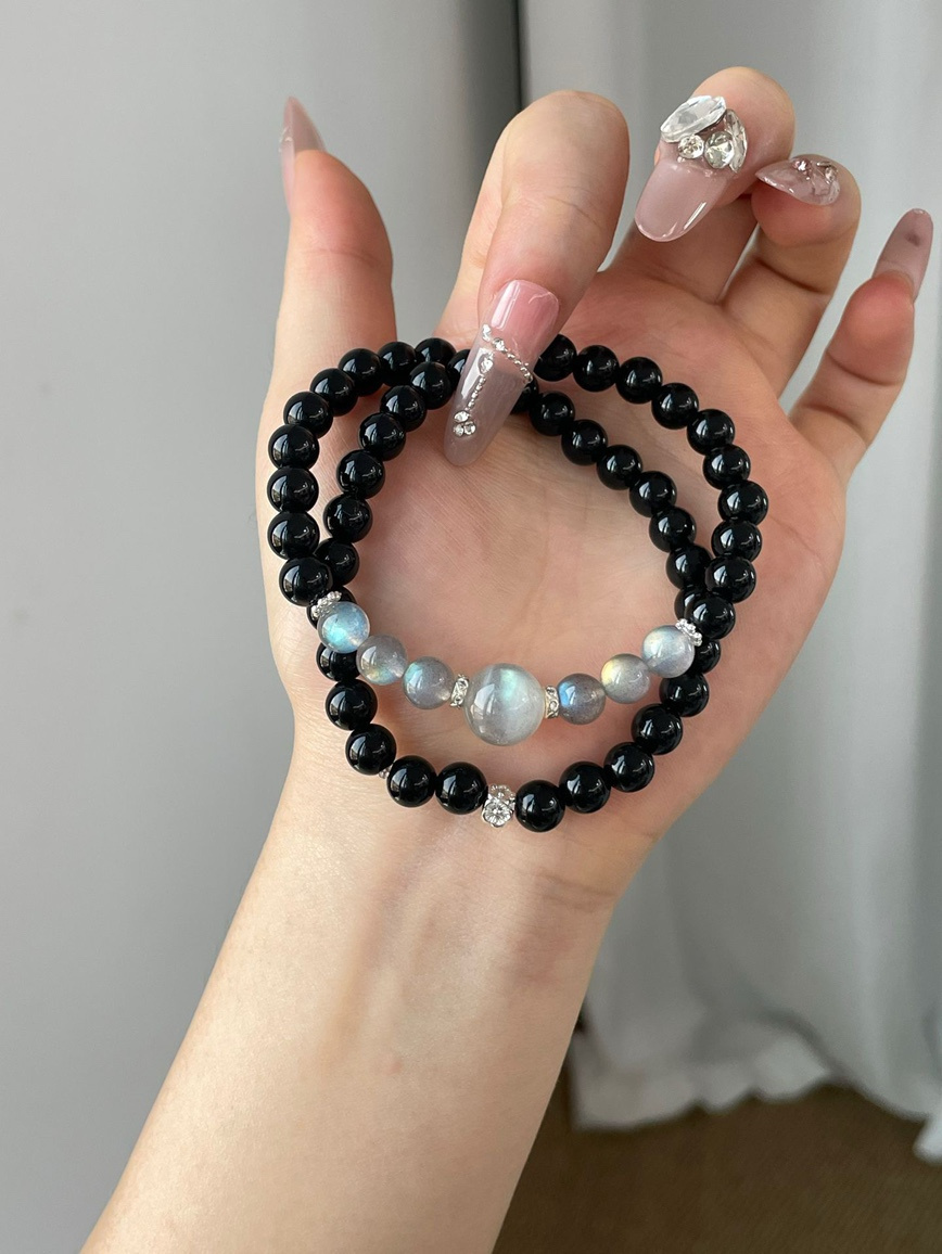Hand holding double-layer Obsidian and Gray Moonstone bracelet with gemstone shine