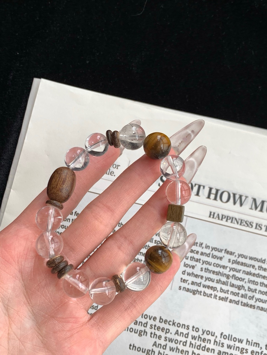 Hand holding natural gemstone bracelet with clear quartz reflection