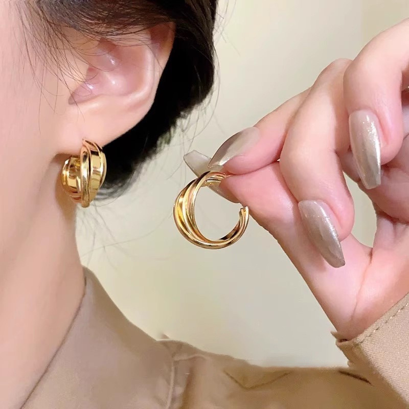 Gold twisted hoop earrings worn on ear with product close-up