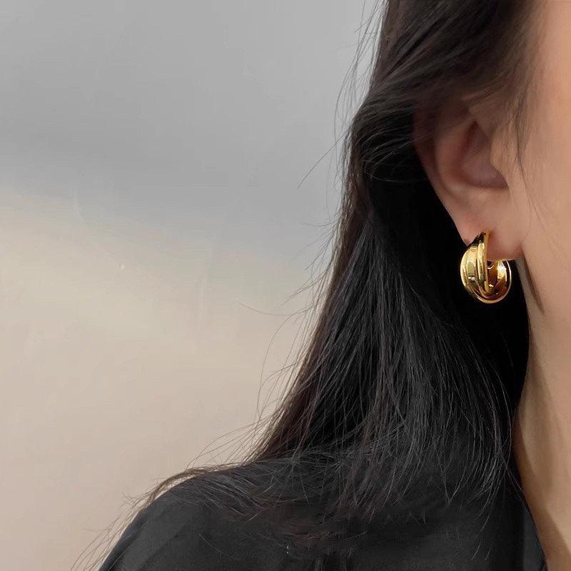  Chunky gold twisted hoop earrings worn with black outfit