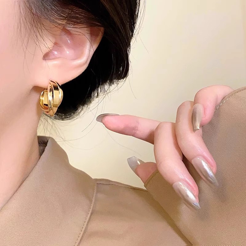 Gold twisted hoop earrings on ear close-up