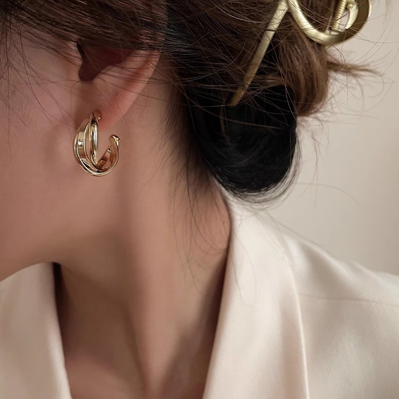 Gold intertwined hoop earrings styled with white blazer
