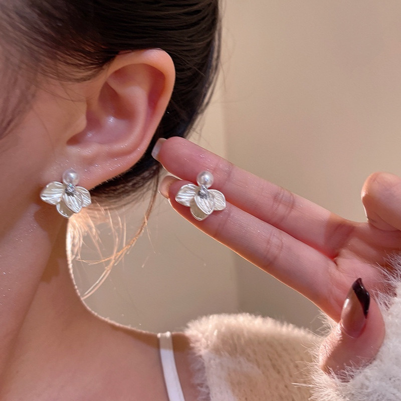 Silver pearl flower stud earrings on ear close-up