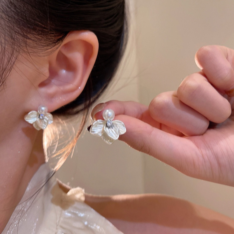 Silver pearl floral stud earrings worn on ear