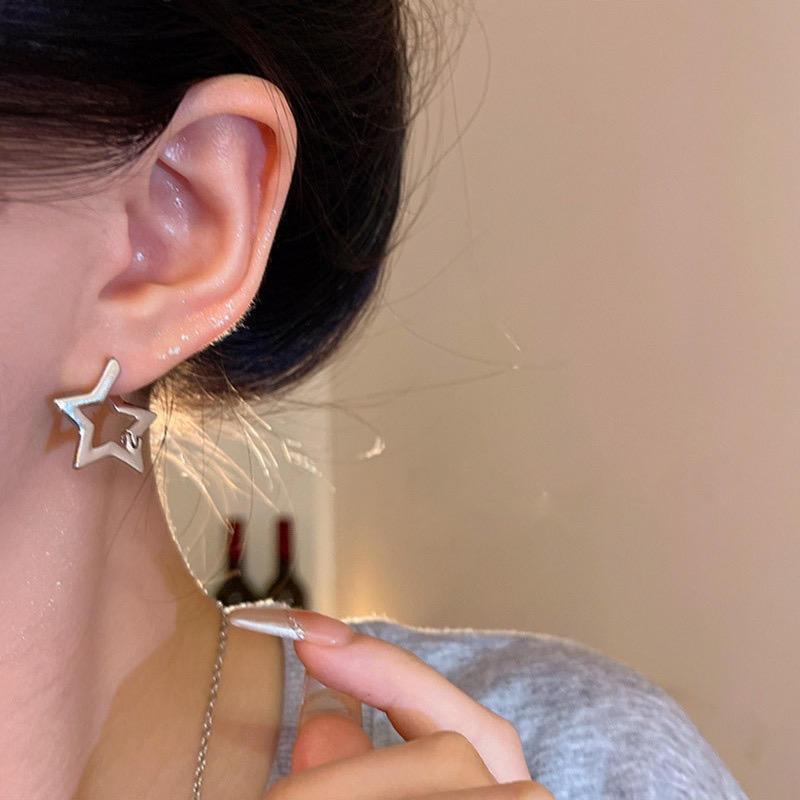 Silver star hoop earrings on ear close-up