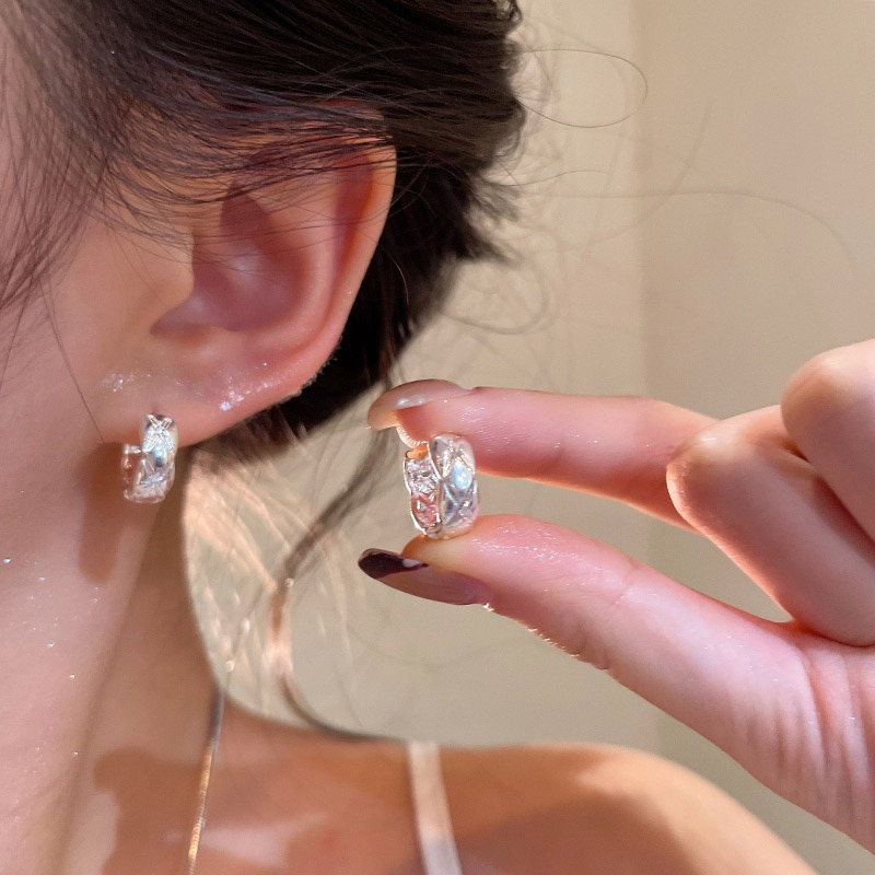 Silver textured hoop earrings worn and held in hand