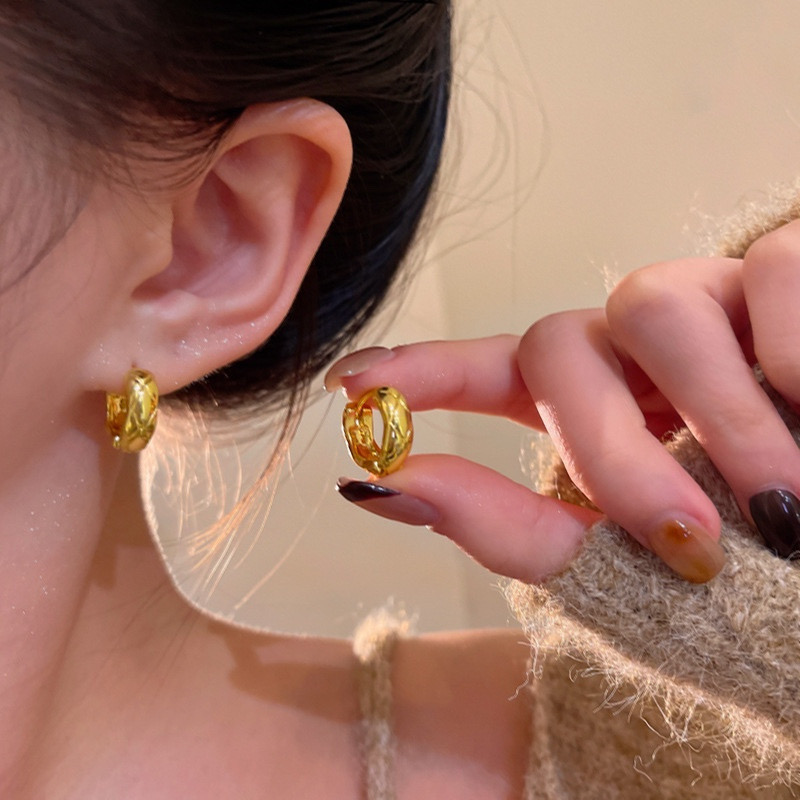 Gold textured woven hoop earrings worn and held in hand