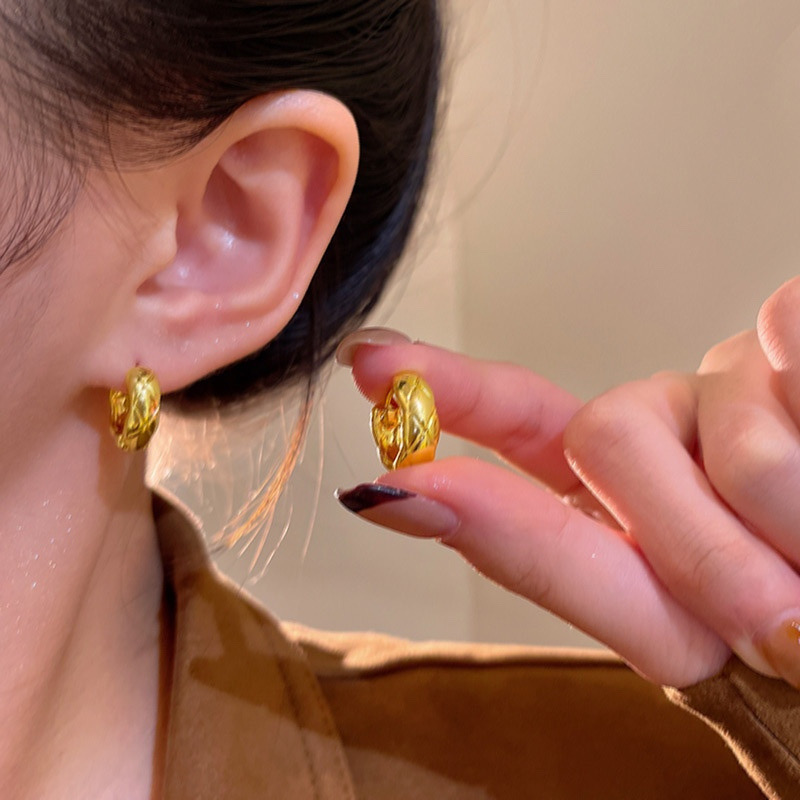 Gold woven hoop earrings worn on ear