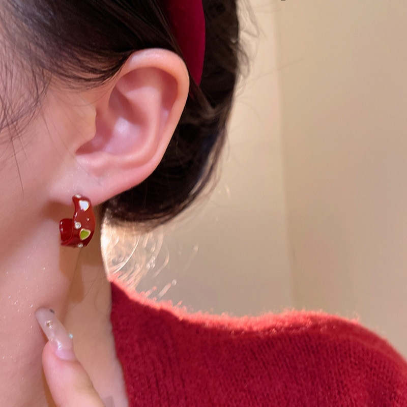 Red heart hoop earrings worn and held in hand